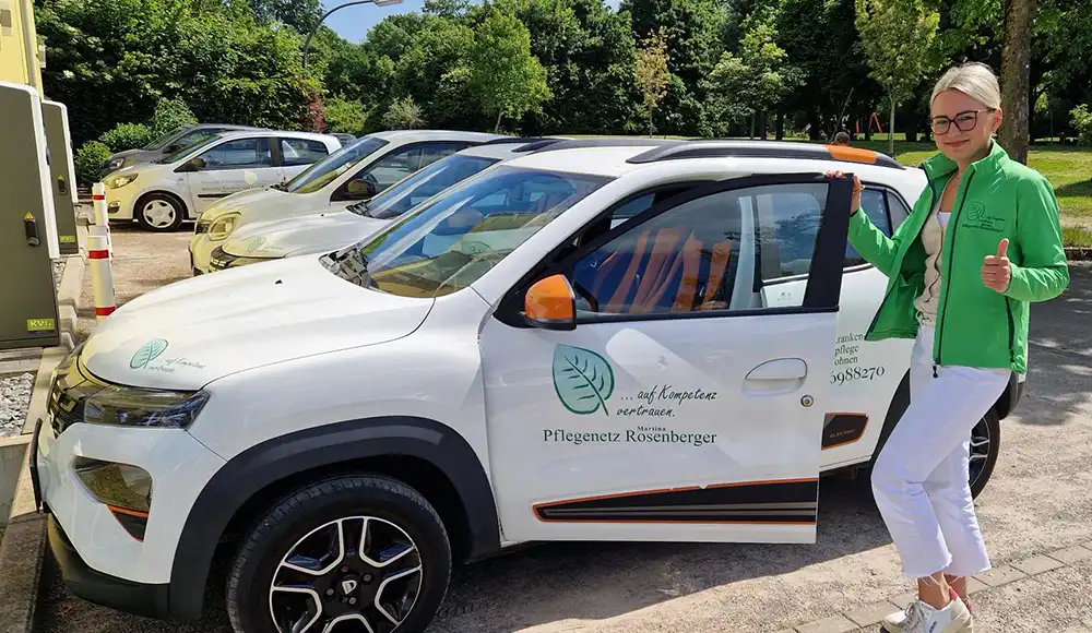 Elektroauto vom Pflegenetz Rosenberger, Castrop-Rauxel, mit einer Mitarbeiterin, die den Daumen der linken Hand hebt